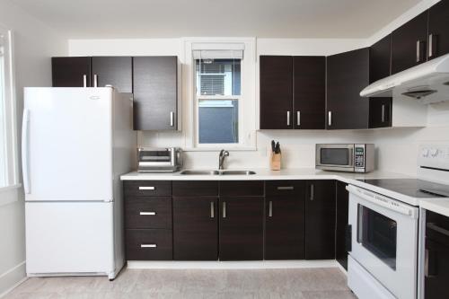 a kitchen with black cabinets and a white refrigerator at Cozy Home in Kitslano, Vancouver. Free Parking. in Vancouver