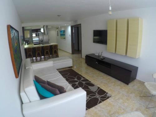 a living room with a white couch and a tv at Lo mejor de isla Margarita in Pampatar