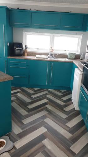 a kitchen with blue cabinets and a checkered floor at 2 bed lodge sleeps 6 in Rhyl