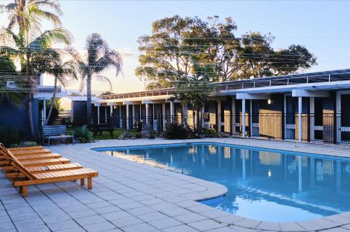a swimming pool with a bench next to a building at Mallacoota Hotel Motel in Mallacoota