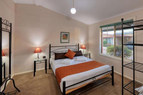 a bedroom with a bed and two lamps and a window at Comfort Inn Crystal Broken Hill in Broken Hill