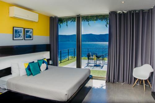 - une chambre avec un lit et une vue sur l'eau dans l'établissement Cardedeu Residence Lago de Coatepeque, à El Congo