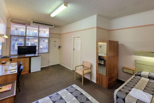 a room with two beds and a desk and a television at Comfort Inn Crystal Broken Hill in Broken Hill