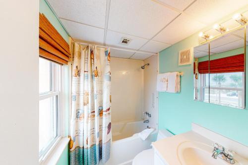 uma casa de banho com uma banheira, um lavatório e uma janela em Treehouse Townhome em Pensacola Beach