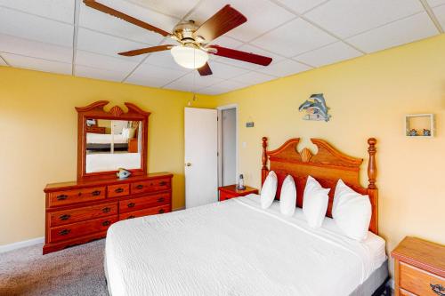 um quarto com uma cama, uma ventoinha de tecto e uma cómoda em Treehouse Townhome em Pensacola Beach