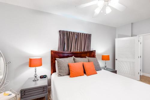 a bedroom with a white bed with orange pillows at Waters Edge 501 in Fort Walton Beach