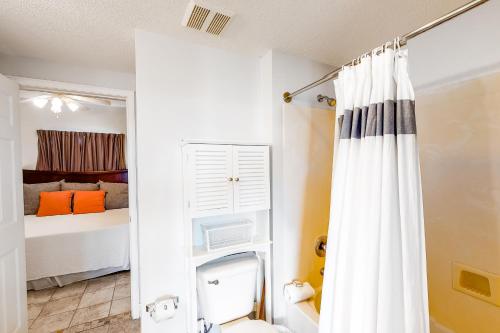 a bathroom with a white shower curtain next to a bed at Waters Edge 501 in Fort Walton Beach