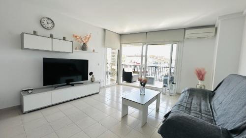 a living room with a tv and a couch and a table at Apartamento con vistas a mar y canal. Empuriabrava in Empuriabrava