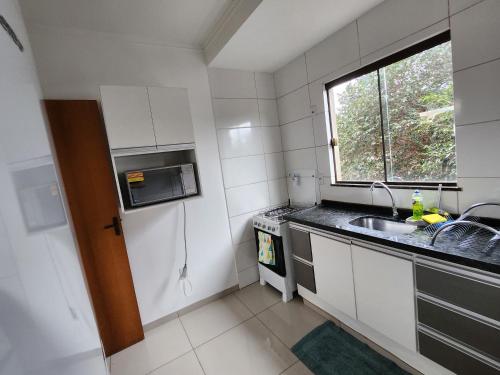 una pequeña cocina con fregadero y ventana en DOURADOS GUEST FLAT PEDRA BONITA, en Dourados