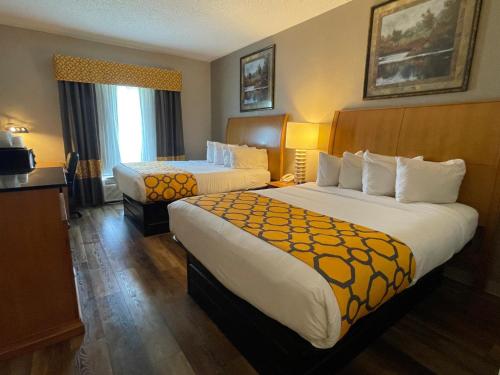 a hotel room with two beds and a television at Baymont by Wyndham West Plains in West Plains