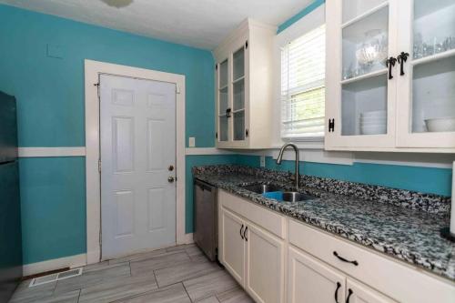 a kitchen with blue walls and white cabinets and a sink at Country Cottage in The Hills in Augusta