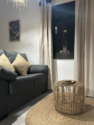 a living room with a couch and a wicker stool at Plaza de la fuente Granadilla de Abona Tenerife sur Only Adults con terraza privada in Granadilla de Abona