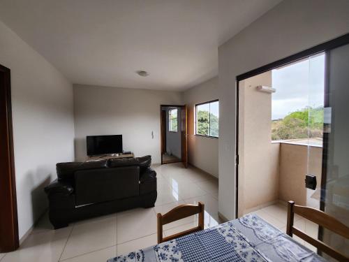 a living room with a couch and a television at DOURADOS GUEST FLAT PEDRA BONITA in Dourados