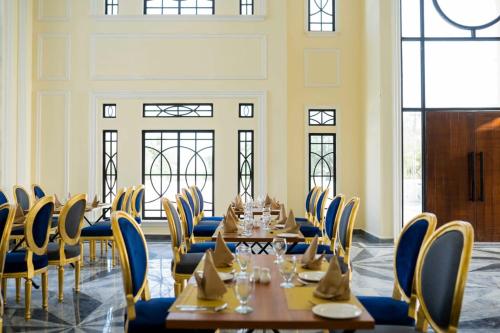 una sala da pranzo con tavoli, sedie e finestre di Falettis Grand Bahawalpur a Bahawalpur