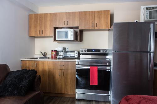 a kitchen with a stainless steel refrigerator and a microwave at Motel LA RÉFÉRENCE in Trois-Rivières