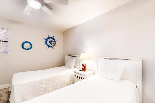 德斯坦的住宿－Tradewinds 07，一间卧室设有两张床,墙上挂着一个时钟。