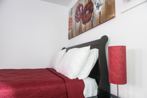 a bedroom with a bed with a red blanket and white pillows at Motel LA RÉFÉRENCE in Trois-Rivières