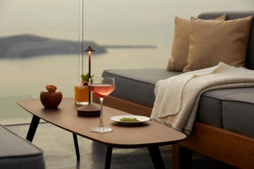 a living room with a table with a glass of wine at Kivotos Santorini - Preferred Hotels & Resorts in Imerovigli