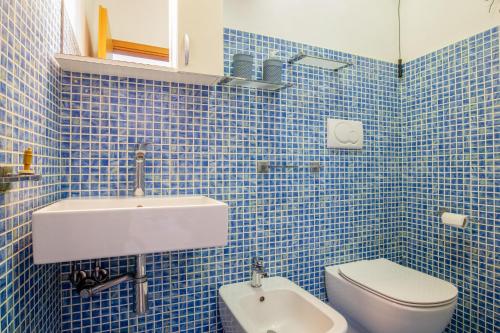 a blue tiled bathroom with a toilet and a sink at Casa Stecchi in Capoliveri