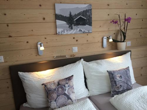 a bedroom with a wooden wall with a bed with pillows at Hotel Terminus in Küblis