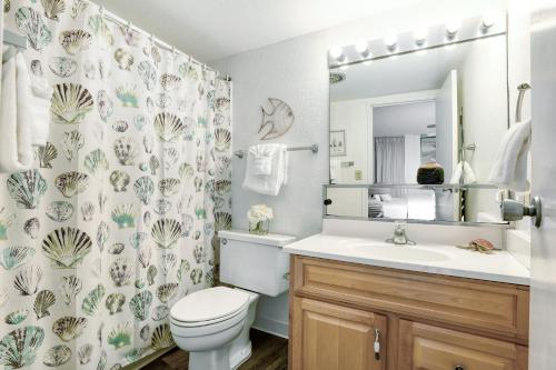 a bathroom with a toilet and a sink and a mirror at Island Sands Resort 302 in Wailuku