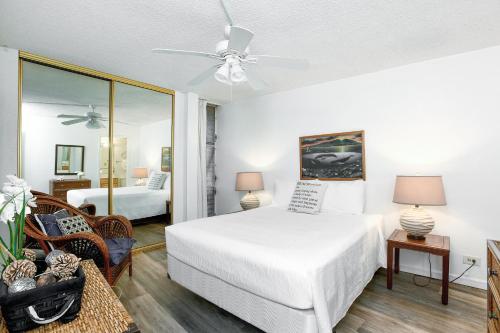 1 dormitorio con cama blanca y espejo en Island Sands Resort 302 en Wailuku