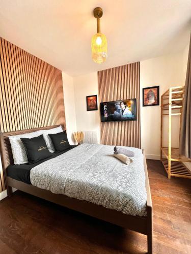 une chambre avec un lit et une télévision au mur dans l'établissement Le Cocon proche Paris JO 2024 Centre-ville, à Saint-Gratien