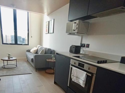 a kitchen and a living room with a couch at Lovely 1 Bedroom Duplex Apartment in Manchester in Manchester