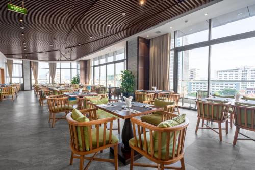 a restaurant with tables and chairs and large windows at G8 Luxury Hotel and Spa Da Nang in Da Nang
