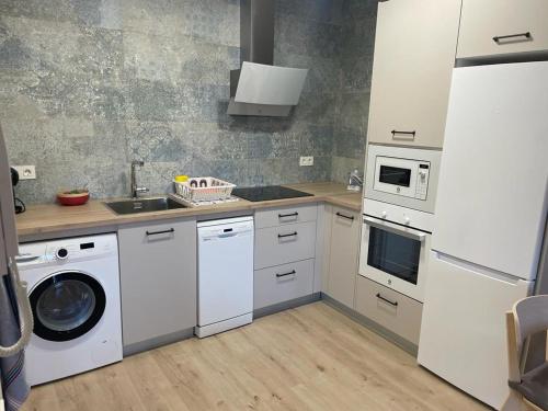 a kitchen with white cabinets and a washer and dryer at VISTAS A SANTO DOMINGO in León
