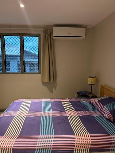 a bedroom with a bed with a purple comforter and two windows at Pacific FairPrice in Nadi