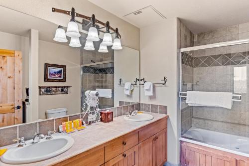 uma casa de banho com 2 lavatórios, uma banheira e um espelho. em Torian Plum Creekside 513 em Steamboat Springs