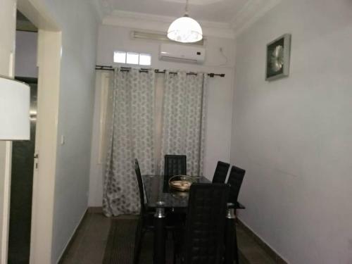 a dining room with a table and chairs and a window at Appartements madame lydie in Pointe-Noire