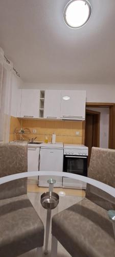 a kitchen with white cabinets and a table and chairs at Apartmani Talija 3 i 4 Sokobanja in Soko Banja