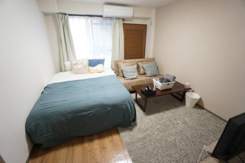 um quarto com uma cama e um sofá em Apartment Febbraio Motomachi 503 em Osaka