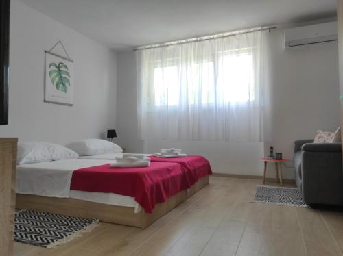 a white bedroom with a bed with a red blanket at Apartment Deeranaei in Kraljevica
