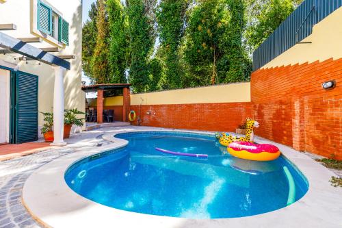 Jacuzzi, garden, pool & barbecue beach House, 15mn from Lisbon center في أويراس: مسبح في فناء خلفي مع طوف قابل للنفخ