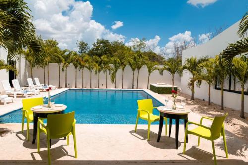 a patio with tables and chairs next to a swimming pool at Hotel & Suites Yuca Ville Siglo XXI in Mérida