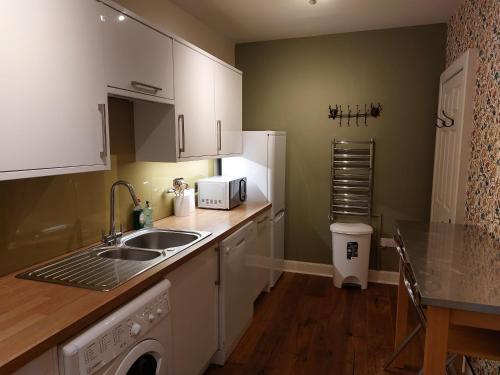 a kitchen with white cabinets and a sink and a table at Stunning 5BR Royal Mile Penthouse in Edinburgh