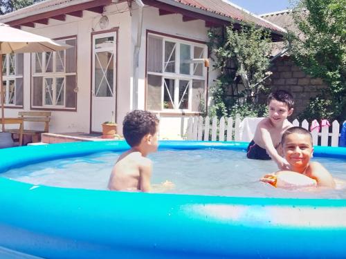 three children playing in a swimming pool at Village Rooms Guesthouse in İvanovka