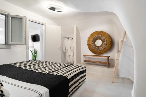 a white bedroom with a bed and a mirror at Spilia Caves Santorini in Akrotiri