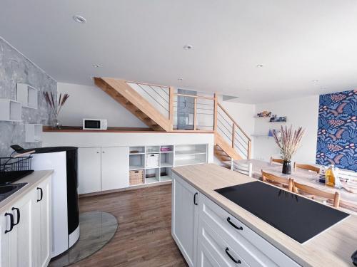 une grande cuisine avec des placards blancs et un escalier dans l'établissement Gîte Familial 3 étoiles - Maison Kidour, à Saint-Frégant