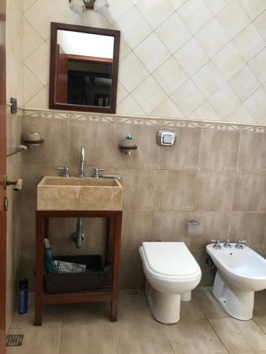 uma casa de banho com um lavatório, um WC e um espelho. em Luis marcelo em Alta Gracia