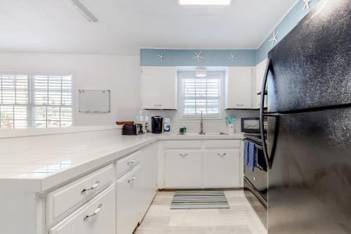 cocina con armarios blancos y nevera de acero inoxidable en Lazy Seagull Beach House, en South Padre Island