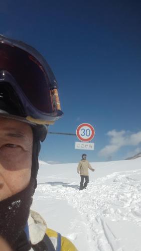 a person standing in the snow with a speed limit sign at Bistare Kana in Niseko