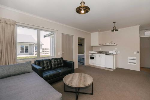 uma sala de estar com um sofá e uma mesa em South Street West Motel em Feilding