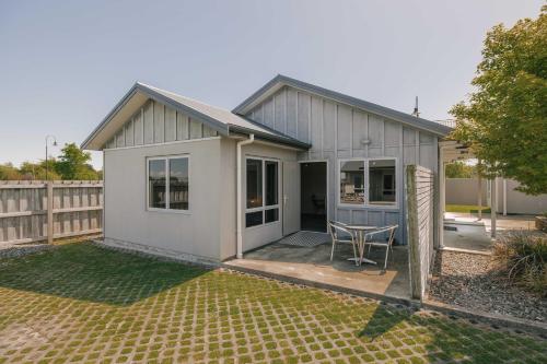 a small white house with a table in a yard at South Street West Motel in Feilding