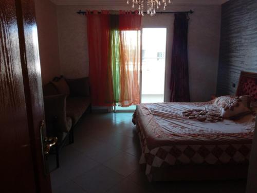 ein Schlafzimmer mit einem Bett, einem Fenster und einem Sofa in der Unterkunft Chez Mostafa in Douar Ourlali