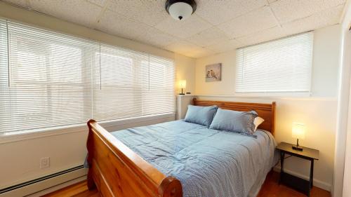Lake Duplex Delight في Vassalboro: غرفة نوم بسرير مع مصباحين ونوافذ اثنين