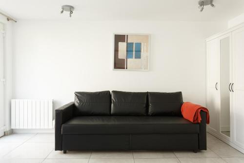 - un canapé noir dans une pièce blanche avec une photo dans l'établissement Le Blanc-Mesnil parc des expos studio RDJD barbecue, au Blanc-Mesnil